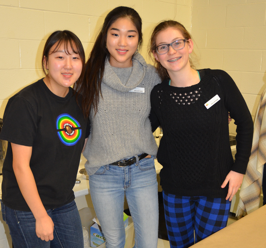 Three teenagers posing together and smiling.