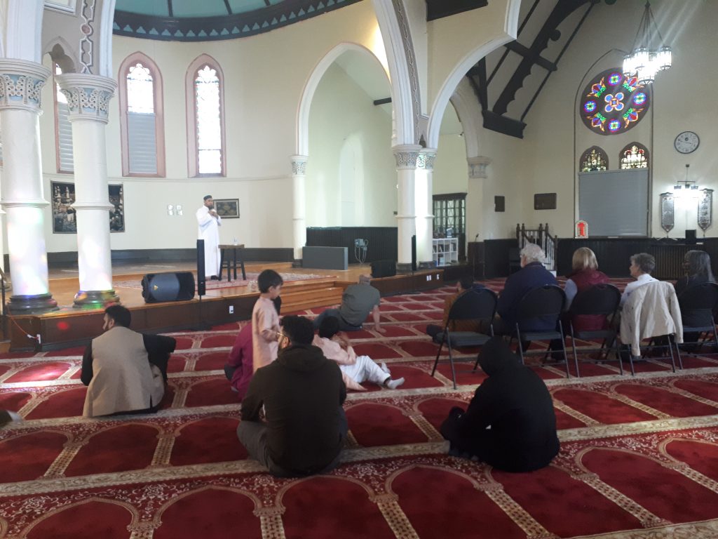 Community members sitting in the mosque at the St. Thomas Islamic Centre, listening to a guest speaker. 