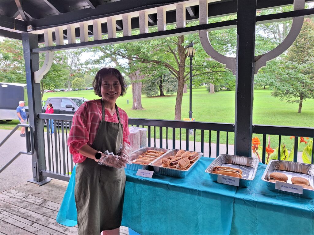 A woman serving hotdogs.