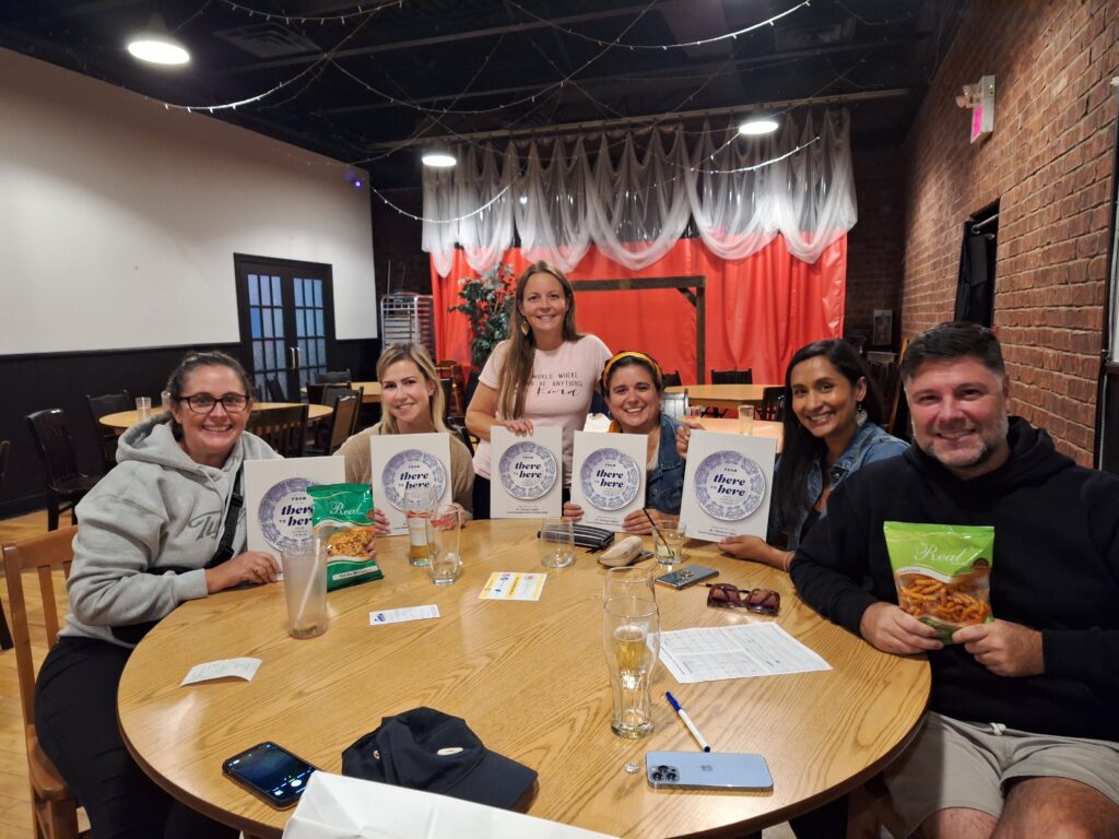 A group of people sitting around a table holding up copies of the STELIP cookbook.